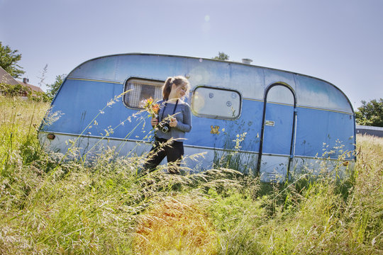 Sweden, Skane, Osterlen, Tomelilla, Teenage girl (14-15) in front of travel trailer in grass 