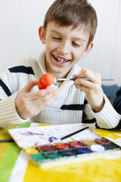 Boy (8-9) decorating Easter eggs