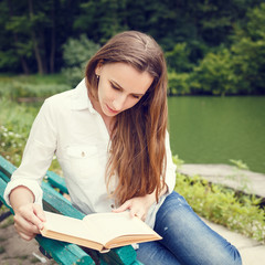 Young woman sitting on the bench and reading book