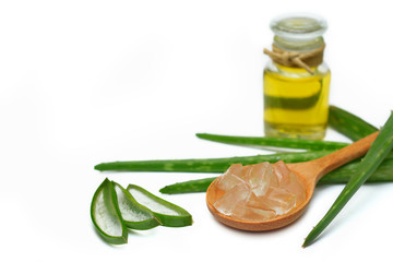 Aloe vera oil in glass bottle with sliced of aloe vera gel and leaves on white background.
