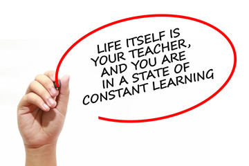 Man writing LIFE ITSELF IS YOUR TEACHER, AND YOU ARE IN A STATE OF CONSTANT LEARNING with marker on transparent wipe board.