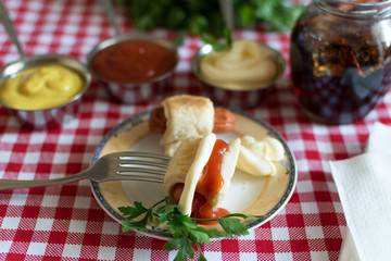 Sausages in dough (Mini hot dog homemade) with ketchup, mayonnaise and parsley on the plate and and cola in a glass jar