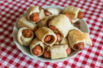 A large plate with a homemade mini hot dogs (hot dogs in pastry) for a large family to the Day of Hot Dog.