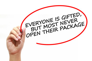 Fototapeta premium Man writing EVERYONE IS GIFTED, BUT MOST NEVER OPEN THEIR PACKAGE with marker on transparent wipe board.