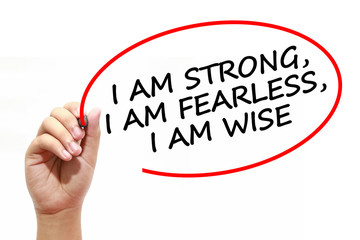 Man writing I AM STRONG, I AM FEARLESS, I AM WISE with marker on transparent wipe board.
