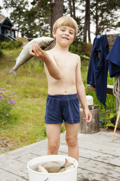 Sweden, Uppland, Runmaro, Barrskar, Portrait of boy (4-5) holding fish