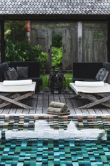 View of pool with set of clean towels and two chaise-longues