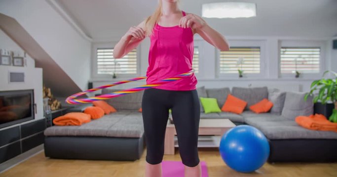 A lady is trying to exercise. She is doing a Hula-Hoop work-out. She's quite good at it. It is a great way to have fun when working out.
