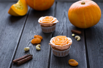 Pumpkin spiced cupcakes with buttercream flowers on a dark wooden background
