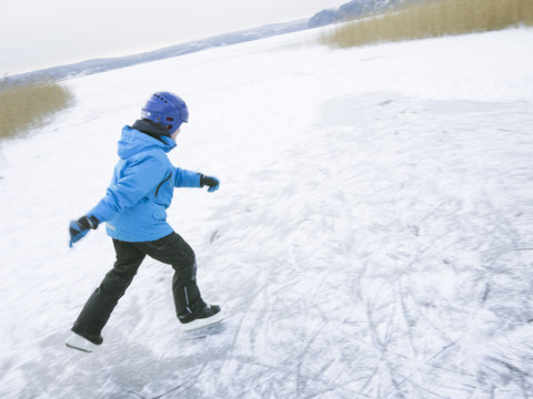 Sweden, Vastergotland, Lerum, Lake Aspen, Boy (10-11) ice-skating on surface of frozen lake