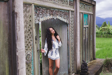 Young beautiful woman walking near old antique house in Bali sty