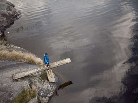 Sweden, Vastergotland, Lerum, Lake Aspen, Boy (10-11) standing on springboard projecting off rocky lakeshore