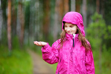 Adorable little girl playing happily in the rain