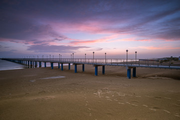 Sunset on the beach after a storm, the pier and the in the evening