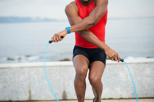 Detail Of Male Runner Jumping Rope For Warming Up. Black Sporty Man Training And Exercising Outside.