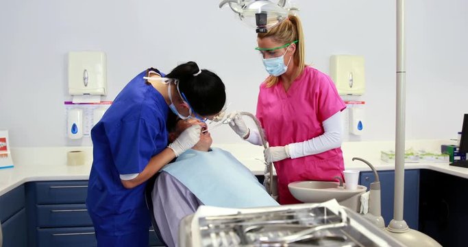 Dentist examining a patients teeth with assistant