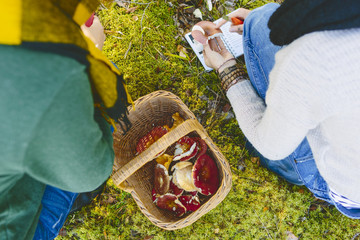 Finland, Etela-Savo, Huttula, Two young women crouching by basketful of Russula mushrooms