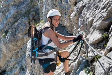 Tuinposter Alpinisme Vrouw in bergbeklimmingsuitrusting die een via ferrata doet