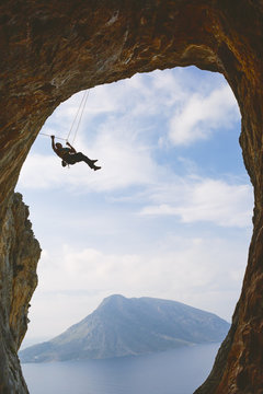 Greece, Dodecanese, Kalymnos, Mountain climbing hanging off natural arch