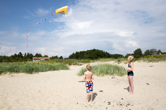 Sweden, Skane, Vejbystrand, Boy (6-7) and girl (10-11) flying kite