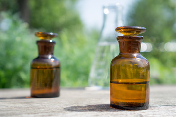 Liquid in chemical ware on a background of plants, fertilizers or pesticides in the garden.