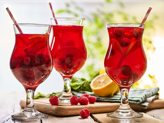 On wooden boards are ice cold beverage glasses with red raspberry lemon cocktail . Alcohol country cocktail beverage number hundred thirty two with drinking straw. Cocktail on outdoor.