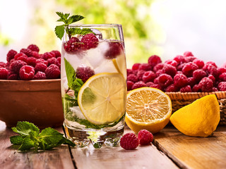 On wooden boards glass with raspberry alcohol cocktail and ice cubes. Cocktail number hundred eighteen cocktail raspberry mojito with raspberry bowl. Country life. Outdoor. Light background.