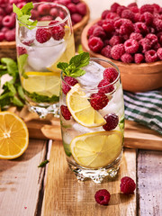 Alcohol cocktail. On wooden boards glasses with ice cubes alcohol cocktail. Cocktail number hundred twenty one cocktail raspberry mojito with lime and mint leaf. Country outdoor. Light background.