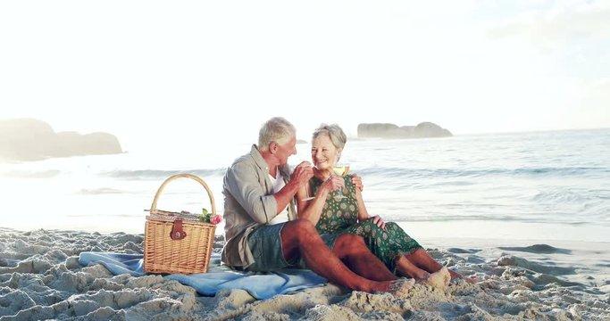 Retired old couple drinking white wine on the beach
