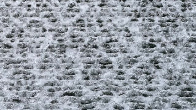 Water flowing down a black wall background.