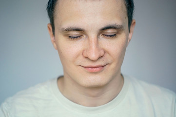 Fototapeta premium Portrait of young man with eyes closed in studio setting