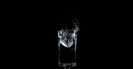 Ice landing in glass of water making a splash