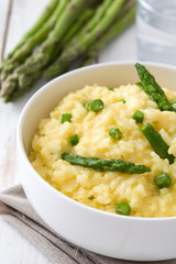 Risotto with asparagus, parsley and peas on a white wooden table

