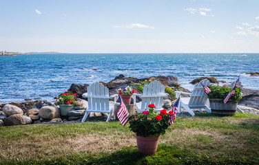 Patriotic flowers on Independence Day holiday next to Adirondack chairs overlooking the bay