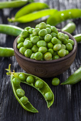 green peas in the pod on a black wooden table.