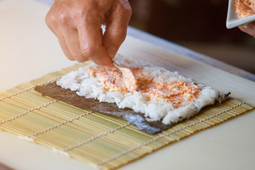 Spoon putting sauce on rice. Small spoon in male hand. Tasty filling for sushi rolls. Recipe from japanese cuisine.