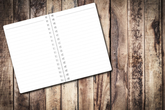 Blank notebook page on old brown wooden table. Notebook empty page white copy space for text or image. Dark edged.
