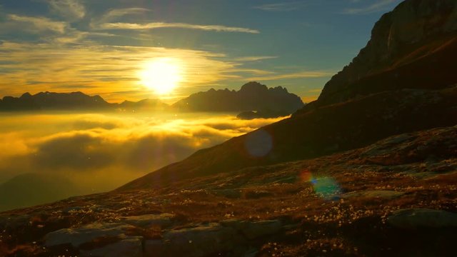 AERIAL: Sunny mountaintop above the sunset clouds