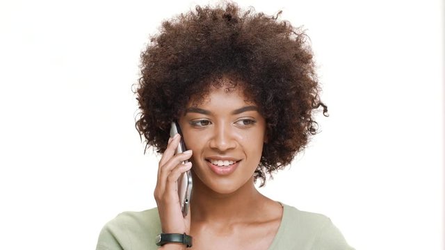 Upset young beautiful african girl speaking on phone over white background.