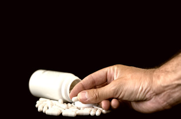 Man's hand holding pill from tablet bottle. Medical concept
