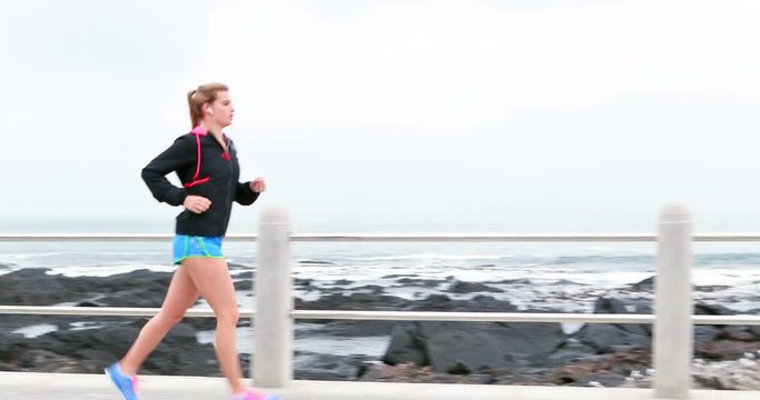 Pretty young determined woman running at promenade