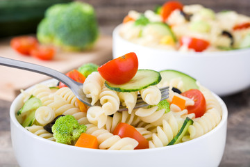 Pasta salad in a bowl on rustic wooden table

