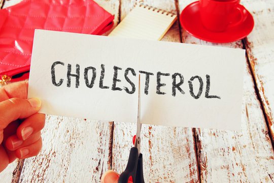 woman hands cutting card with the word cholesterol