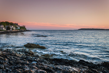 Sunset over Linekin Bay in Ocean Point, Maine, as the low tide gentle sweeps the prominent rocky coast with beautiful home in background