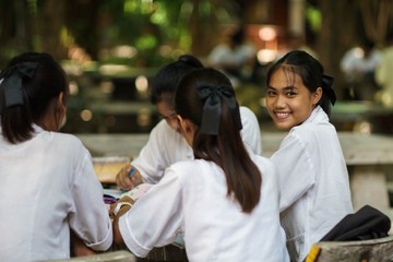 Young thai student reading book and working in the park.