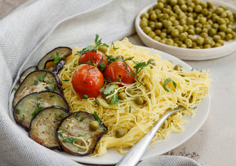 Spaghetti with green peas and fried tomatoes and eggplant