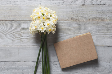 White narcissus flowers and notebook on wooden background