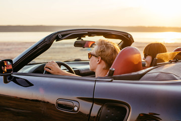 young happy couple in cabriolet in sunset light
