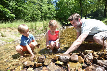 Father and kids in river building a dam with pebbles © goodluz