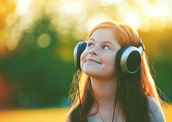 redhead girl with headphones listening to music. space for text
